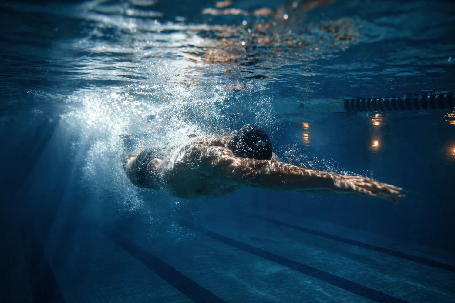 Nageur en crawl sous l'eau, couloir de piscine — vue immergée